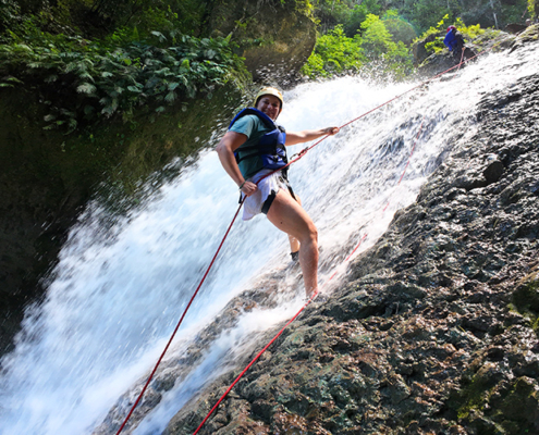 Canyoning mit der Länderexpertin Anastasia Taran. Sie seilt sich an einem Wassefall ab
