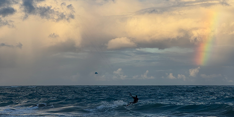 Kitesurfer mit einem Regenbogen im Hintergrund